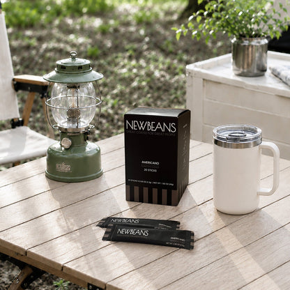 Newbeans Americano box and sticks on a camp table with a travel mug