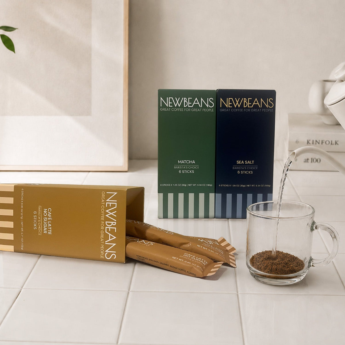Newbeans boxes and sticks on a home kitchen counter beside a glass of latte